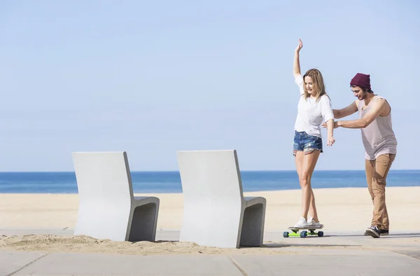 Boy teaching girl balancing on skateboard — Stock Photo, Image