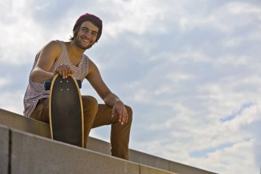 Gülümseyen kaykaycı somut adımlar üzerinde oturan