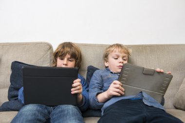 Boys playing games on tablets clipart