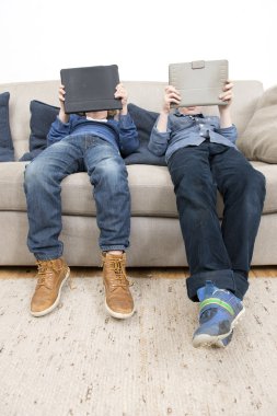 Tablet üzerinde oyunlar oynayan çocuklar