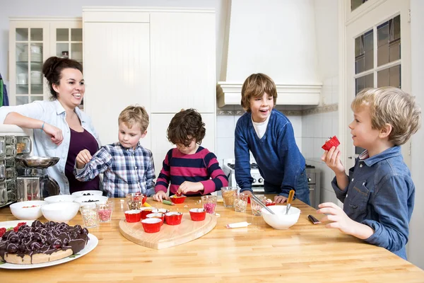 Moeder en kinderen versieren cupcakes — Stockfoto