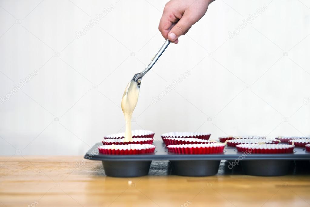 Hand pouring batter into cups