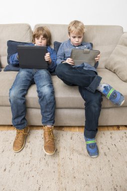Two boys playing video games on a tablet computer clipart