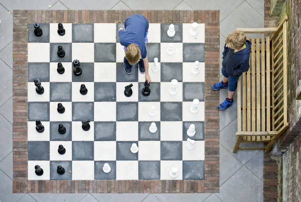 Два мальчика играют в шахматы на открытом воздухе — стоковое фото