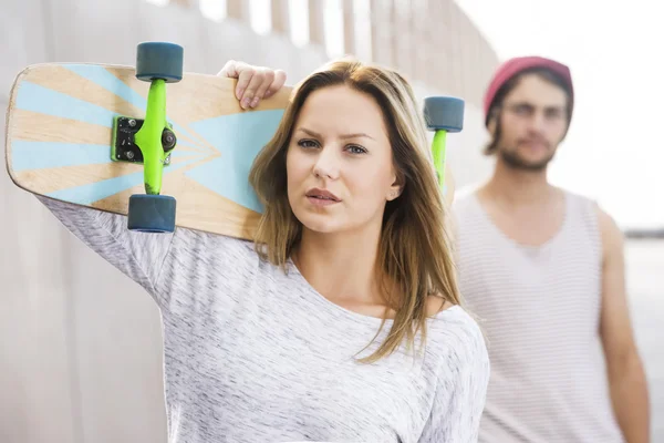 Женщина со скейтбордом на плече — стоковое фото