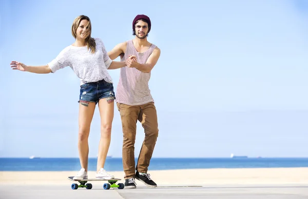 Mann hilft Frau auf Skateboard — Stockfoto