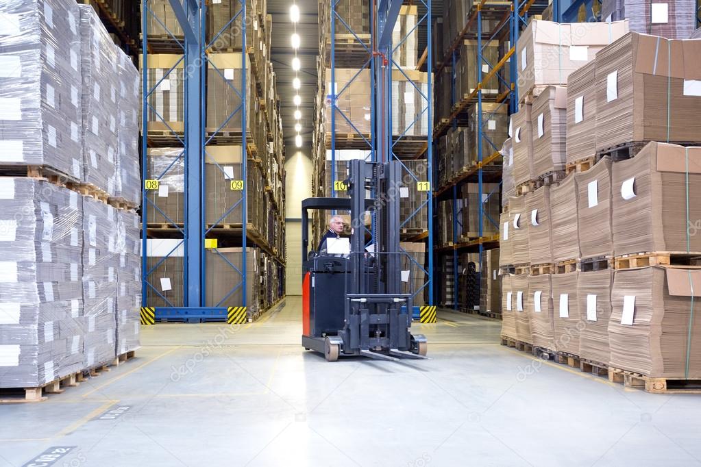 Worker In Forklift Examining Stock