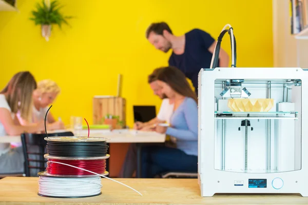 Impresora 3D con diseñadores en segundo plano —  Fotos de Stock
