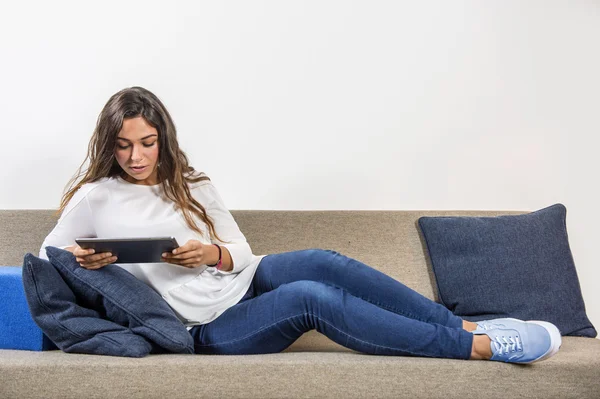 Genç kadın bir kanepede tablet ile — Stok fotoğraf