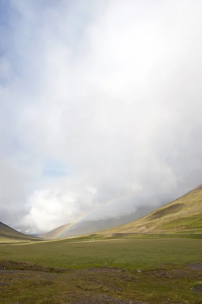 Regenbogen über der grasbewachsenen Tundra Stockbild