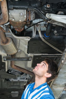 Mechanic examining the exhaust of a car clipart