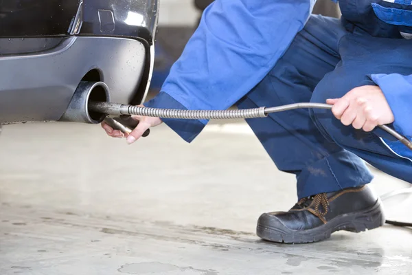 Mechanic checking the exhaust fumes — Stock Photo, Image