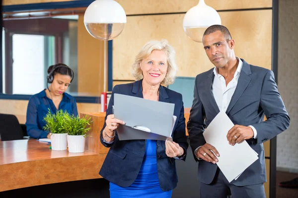 Empresarios de pie en el mostrador de recepción — Foto de Stock