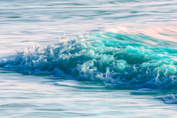 Яркая голубая волна обрушивается с белой пеной, динамичный ирландский морской прибой освещенный естественным светом вдоль побережья.