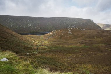Uzak Wicklow Dağları Lough Bray 'de manzara, Corrie Gölü, sonbahar fundası, yosun yamaçları, dramatik gökyüzü.