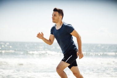 Güneşli kumsalda koşan adam