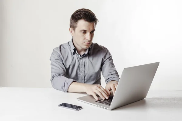 Immagine ravvicinata di uomo d'affari multitasking utilizzando un computer portatile e un telefono cellulare — Foto Stock