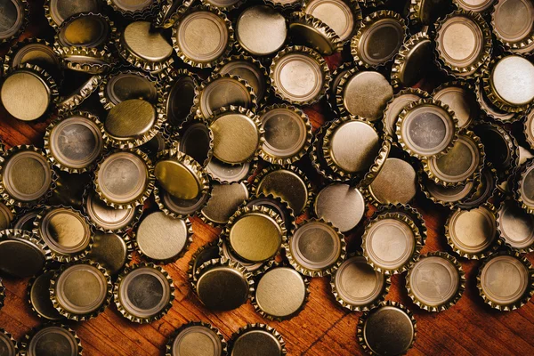 Grande pilha de tampas de garrafa de cerveja na mesa de madeira — Fotografia de Stock