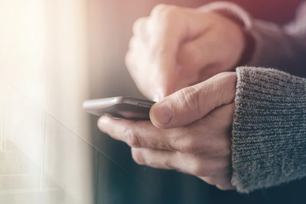 Casual man texting message on smartphone, morning sunlight throu — Stock Photo, Image