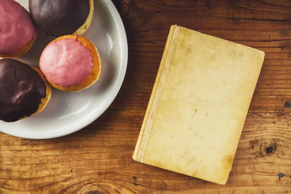 Plate with tasty donuts and vintage book, top view — Stock Photo, Image
