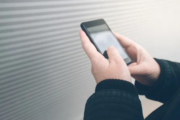 Femme utilisant un smartphone dans la rue face au mur — Photo