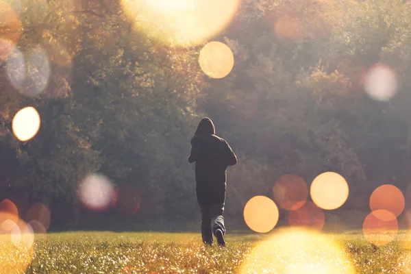 Hooded man jogging in the park — Stock Photo, Image