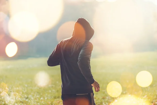 Oigenkännlig hooded man jogga utomhus — Stockfoto