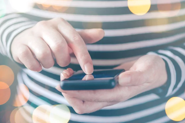 Woman texting message on smartphone, sunshine through the window — Stockfoto