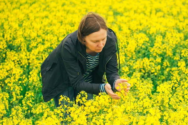 Mujer agrónoma examinando flor de colza oleaginosa floreciendo — Foto de Stock