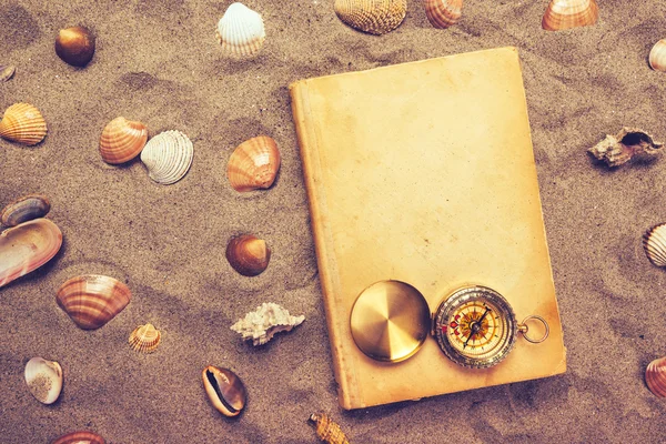 Vintage knižní a kompas na písečné pláži — Stock fotografie