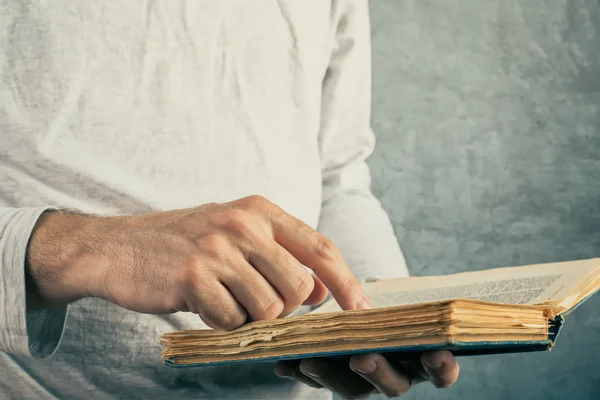 Man reading old book with torn pages — Stock Photo, Image