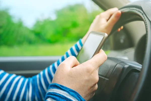 Conducción femenina coche y mensajes de texto SMS mensaje en el teléfono inteligente — Foto de Stock