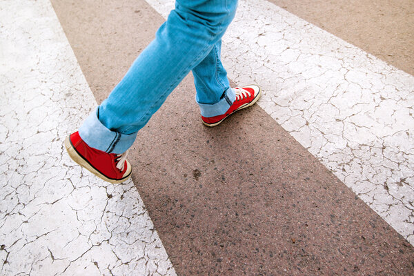 Young teenage person walking over pedestrian zebra crosswalk