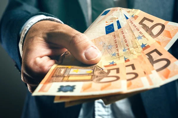 Biznesmen z banku oferuje pożyczki pieniędzy w obiegu banknotów euro — Zdjęcie stockowe