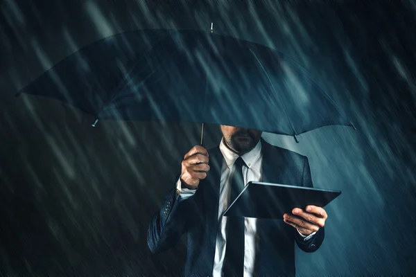 Businessman reading business news on digital tablet in rain — Stock Photo, Image