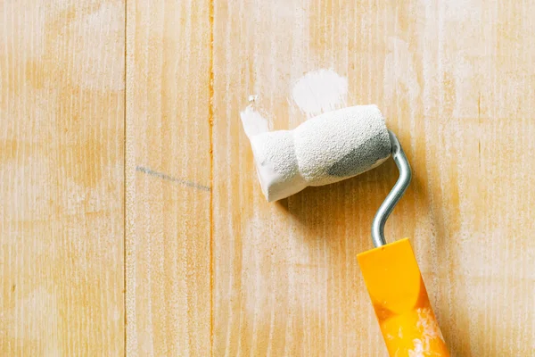 Mano con rodillo de pintura aplicando laca acrílica sobre tabla de madera — Foto de Stock