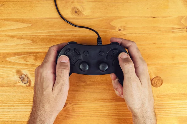 Hands using gamepad controller on wooden desk, top view — Stock Photo, Image