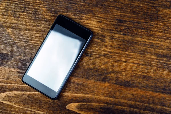 Використовуваний смартфон на дерев'яному офісному столі — стокове фото