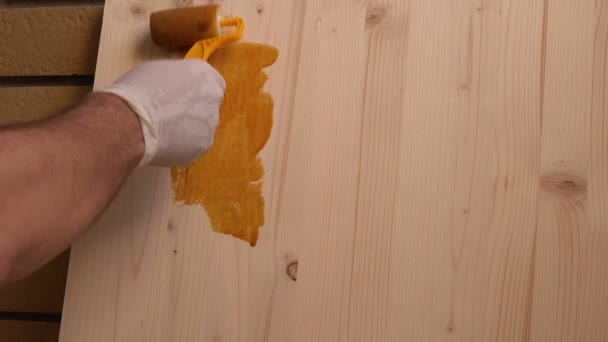 Mano con rodillo de pintura aplicando laca acrílica sobre tabla de madera — Vídeo de stock