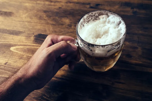 Ruka držící pivní hrnek plný studené čerstvé alkoholického nápoje — Stock fotografie
