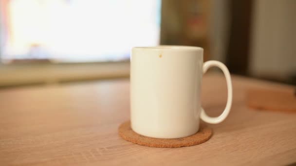 Morgenkaffee in weißer Tasse mit Fernseher im Hintergrund — Stockvideo