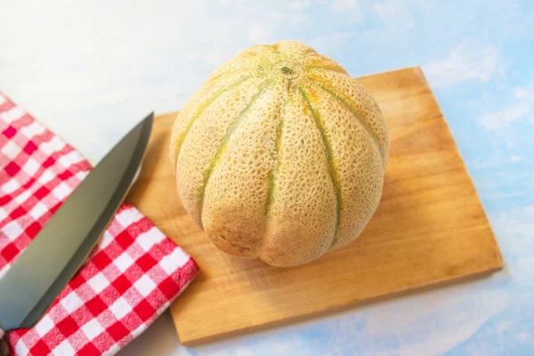 Cantaloupe melon and knife on rustic wooden table — Stock Photo, Image