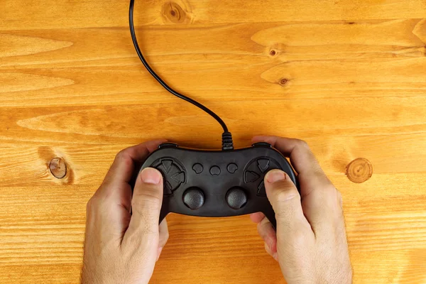 Uomo che utilizza il controller pad di gioco sulla scrivania di legno, vista dall'alto — Foto Stock