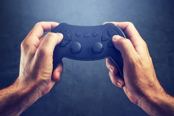 Uomo che utilizza il controller pad di gioco per giocare ai videogiochi — Foto Stock