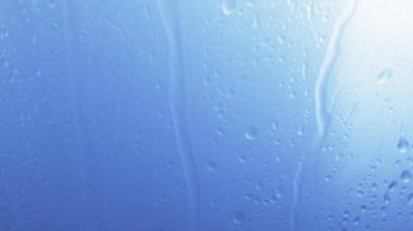 Su ile mavi arka plan cam yüzeyine düşer