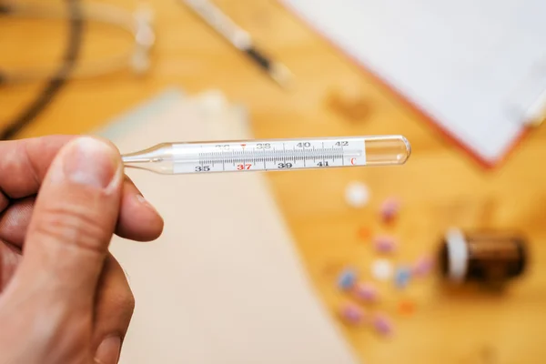 Ruka s lékařský teploměr měřící teplotu lidského těla — Stock fotografie