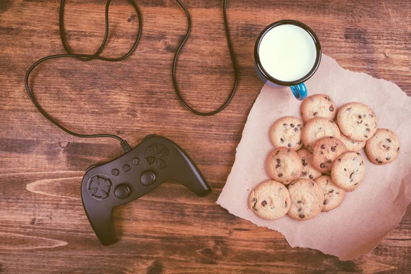 Gamepad and homemade chocolate chip cookies on rustic wooden tab — Stock Photo, Image