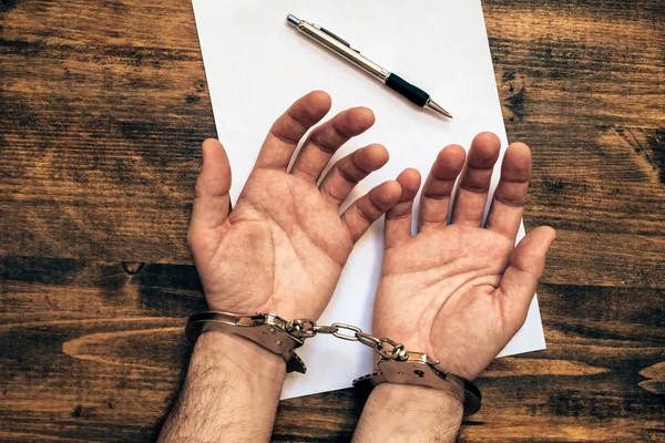 Manos masculinas esposadas, vista superior del escritorio del investigador de la policía — Foto de Stock