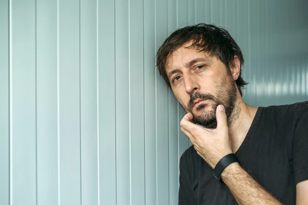 Pensive adult unshaven man with hand on chin — Stock Photo, Image