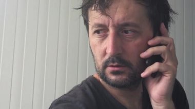 Yorgun ve bitkin adam cep telefonu üzerinde konuşurken